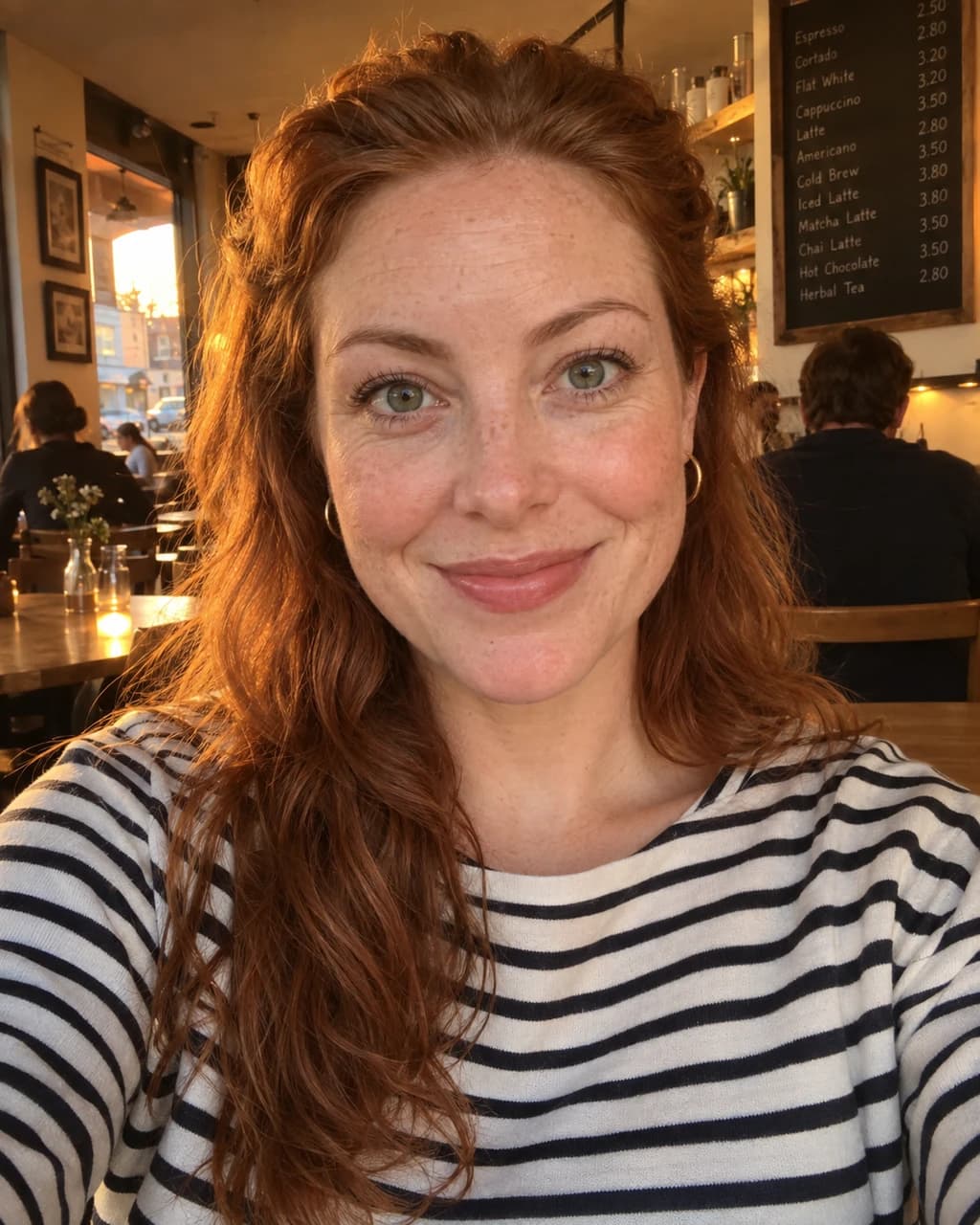 Example person 3: an AI-generated selfie of a woman in her thirties with light freckled skin, copper-red wavy hair and green eyes.